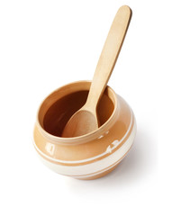 Glazed ceramic pot for cooking with wooden spoon on a white background with clipping path