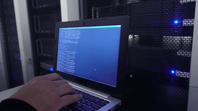 Data Center Engineer Holds Laptop and tests the stability of the system. The image has a slight noise.