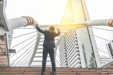 Celebrating success. Low angle view of successful businessman with arms up celebrating his victory...