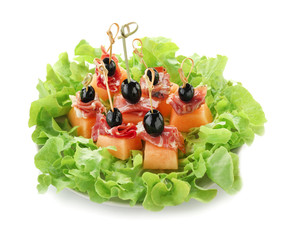 Delicious canape with melon, prosciutto and olives on plate against white background