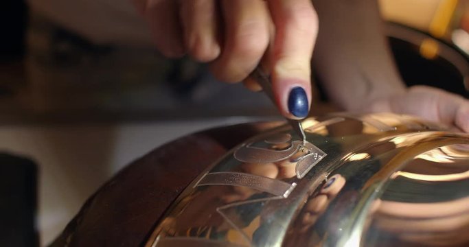 Engraving burin on the bell. Woman engraver, stabs engraving on the bell.