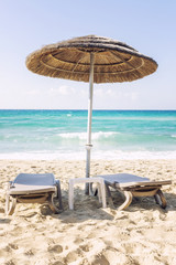 Relaxing scene on a breezy day at the tropical beach, two deck chair and umbrella
