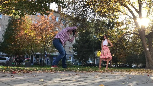 photographer and model take photos at an autumn photo shoot on a city street