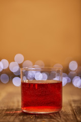 close up view of tasty mulled wine in glass on wooden surface with defocused bokeh lights on backdrop