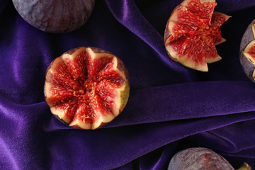 Fresh ripe purple figs on color fabric, top view