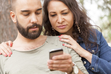 jealous woman spies on him her partner reading message on smart phone. man typing message on mobile...