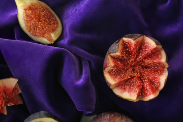 Fresh ripe purple figs on color fabric, top view