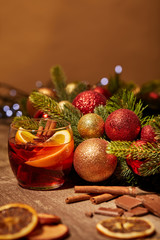 Fototapeta na wymiar close up view of mulled wine drink in glass and pine tree with christmas toys on wooden surface