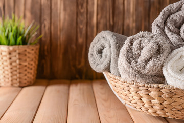 Obraz na płótnie Canvas Wicker basket with rolled clean soft towels on wooden table