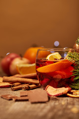 close up view of tasty mulled wine drink, chocolate and pine tree branch on wooden surface