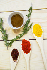 Cooking Hot Spicy Food Concept. Dry spices, beans and herbs in wooden spoon and plastic cup on light wooden table