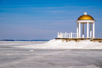 The white rotunda is on the island in the middle of a frozen lake 