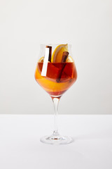 close up view of tasty mulled wine with orange pieces on white tabletop on grey background