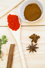 Cooking Hot Spicy Food Concept. Dry spices, beans and herbs in wooden spoon and plastic cup on light wooden table