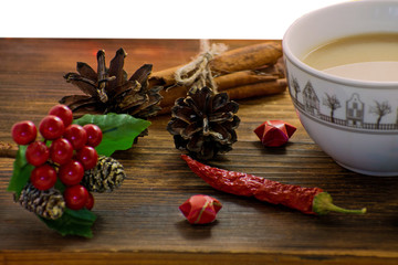 Coffee, spices and pine cones on a wooden background. Christmas concept. A cup of hot coffee with milk, cinnamon and chili on a wooden table.