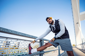 Young active man doing stretching on the bridge before training
