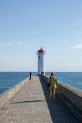 Femme marchant vers le phare à l'entrée du port d'Audierne (Finistère)