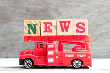 Toy fire ladder truck hold letter block in word news on wood background