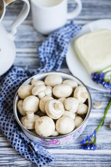 raw champignon mushrooms in a ceramic pot on a wooden table