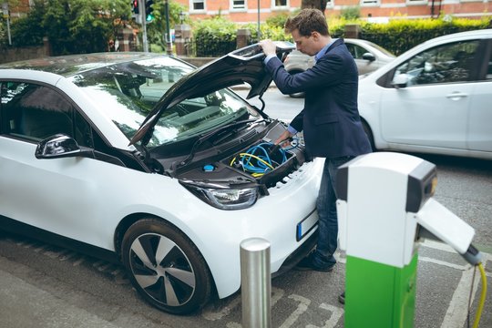 Businessman charging electric car at charging station