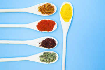 Cooking Hot Spicy Food Concept. Dry spices and herbs in wooden spoons, light blue background