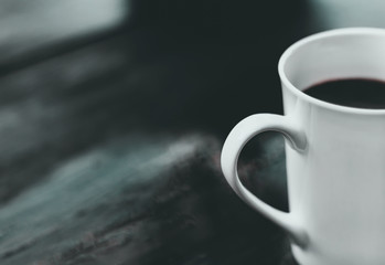 A cup of coffee was placed alone on a wooden table.  The concept of the lonely people heartbroken.