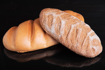 Two loafs on a black background, fresh pastry concept