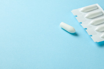 Suppository for anal or vaginal use on a blue background. Candles for treatment of hemorrhoids, temperature, thrush, inflammation