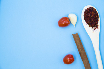 Cooking Hot Spicy Food Concept. Dry spices in wooden spoon, herbs and chili pepper on a light blue backhround