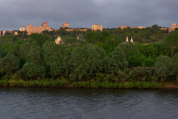 The city on the Bank of the river is surrounded by green trees.