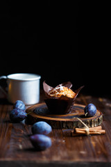 blueberry muffin cupcake on a dark wooden background with plums