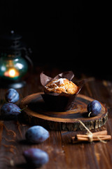 blueberry muffin cupcake on a dark wooden background with plums