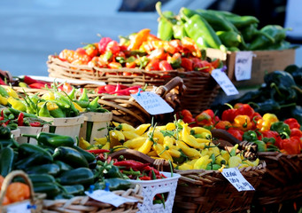 Farmers market goods display.Stand with assorted colorful peppers for sale in sunlight at seasonal farmers market in a shallow depth of field.Agriculture and farming background, small business concept