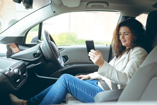 Businesswoman using mobile phone while driving car