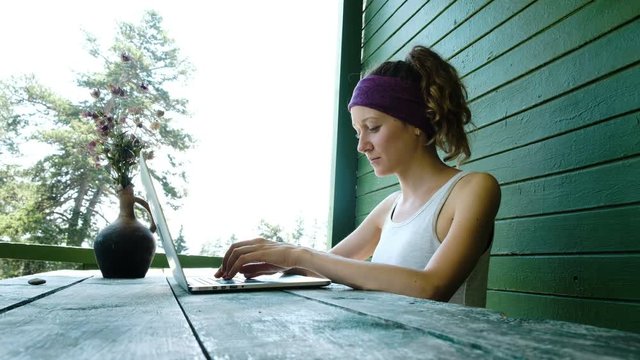 Young business woman tourist freelancer typing on a laptop in the summer outdoors at the recreation center