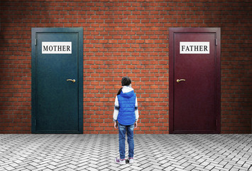 Family conflict. A little girl is standing in front of two closed doors with plates Mother and...
