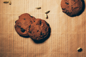 Top view of crunchy chocolate biscuits with cardamom on textured parchment backdrop. Space for your text and design