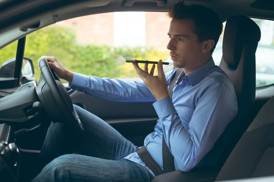 Businessman talking on mobile phone while driving a car 