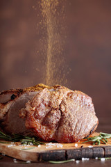 Oven-baked pork with rosemary and spices on a wooden table.