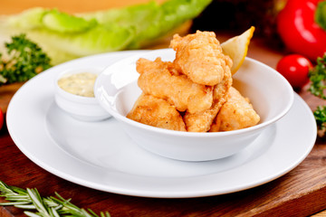 Crispy deep fried fish served with sauce on white plate. Close up