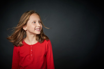 Happy girl with hair flying on wind looking to side at blank copy space, studio portrait