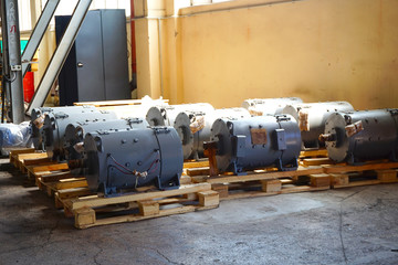 The electric motors are on a rack in a warehouse, in production.