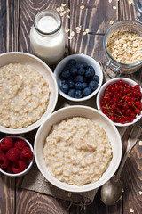 homemade oatmeal and berries on wooden table, vertical top view