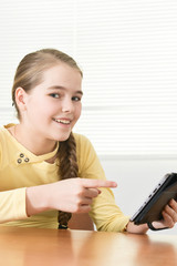 Portrait of teen girl sitting at table and using tablet