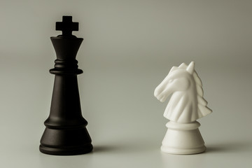 white horse chess and  black king chess stand encounter on a chessboard. - Business winner and...