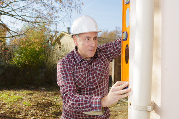 builder checking the straightness of drainpipe
