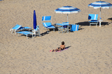 Fototapeta na wymiar spiaggia deserta con ombrelloni e bagnante