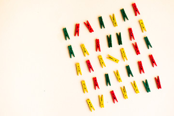 Mini clothespin colored in yellow,red, and green are arranged in row and diagonal shape on a yellow background, back to school theme.