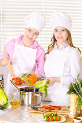 Portrait of two cute girls cooking on kitchen