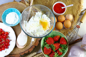 homemade cooking dough on cheese pancakes with strawberry, cherries on a white wooden background, process to cook, flat lay
